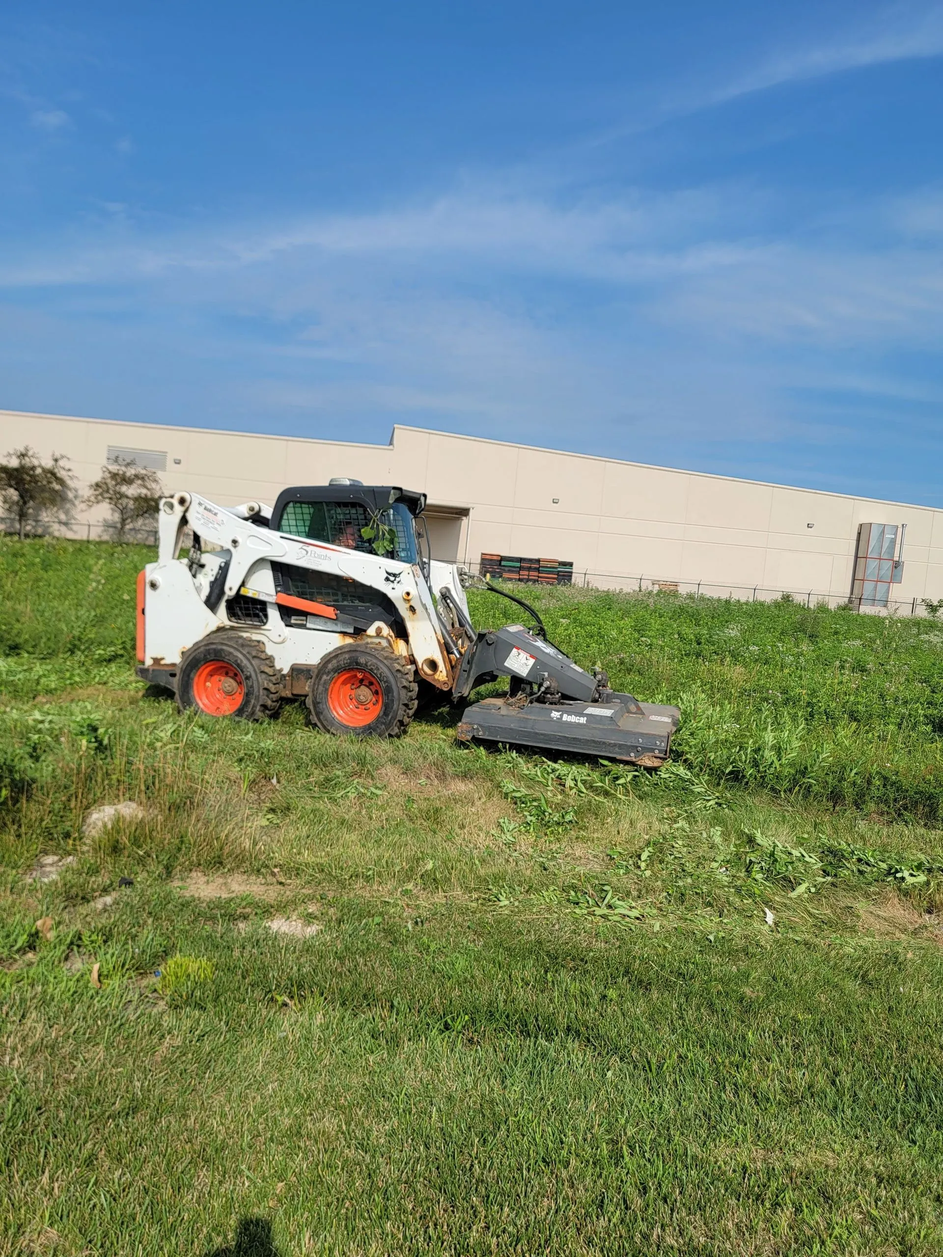 5 Points Landscaping Bobcat clearing grounds at a commercial property